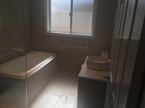 een badkamer met een bad, een wastafel en een toilet bij Doug n Nins Family Home in Forbes