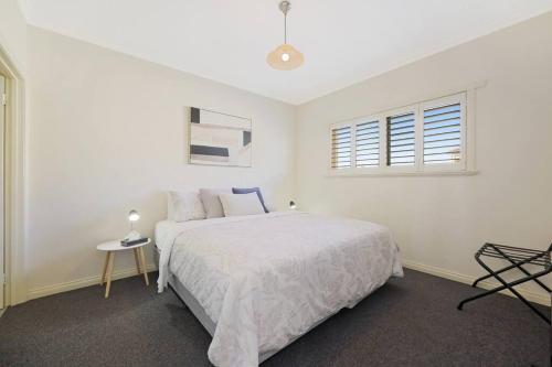 a white bedroom with a bed and a window at One bedroom apartment in CBD in Warrnambool