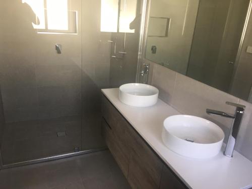La salle de bains est pourvue de 2 lavabos et d'un miroir. dans l'établissement Doug n Nins Family Home, à Forbes
