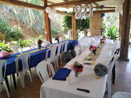 une rangée de tables avec des chaises blanches et des nappes bleues dans l'établissement Reserva Natural Cascadas de Padilla, à Lérida