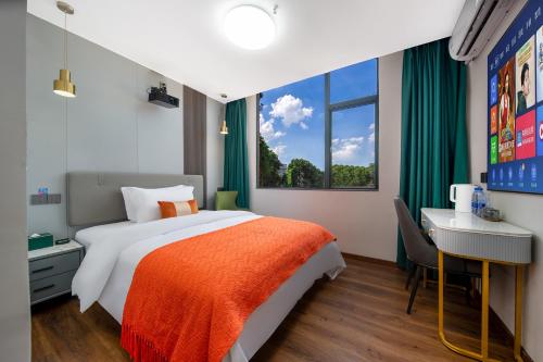 a bedroom with a bed and a desk and a window at Guangzhou Yashay International Apartment - Pazhou Convention and Exhibition Centre in Guangzhou