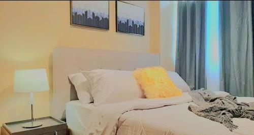 a bedroom with a white bed with a yellow pillow at The Lancris Residences, 2 Bedrooms, 1 Bathroom, Livingroom & Kitchen Pool is free! in Manila