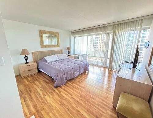 a bedroom with a bed and wooden floors and windows at Ilikai Apt 1618 - Spacious 2BR 2BA Unit with Stunning Ocean-Lagoon View in Honolulu