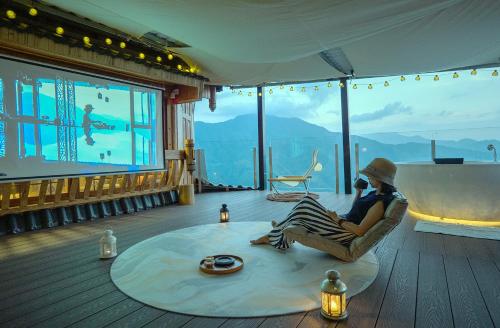 a person sitting in a chair in a room with a large window at Longji One Art Hotel in Longsheng