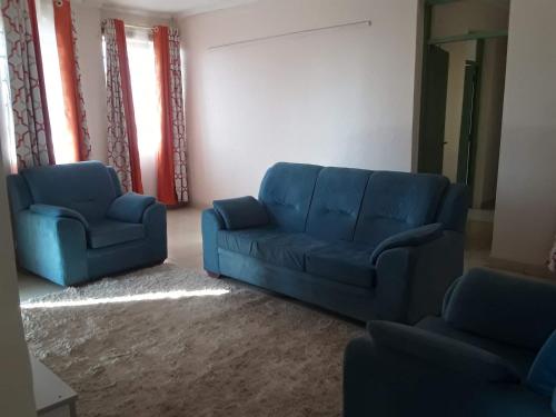 a living room with a blue couch and two chairs at Fid's Place in Nyahururu