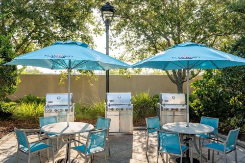 two tables and chairs with blue umbrellas at TownePlace Suites Orlando at FLAMINGO CROSSINGS® Town Center/Western Entrance in Orlando