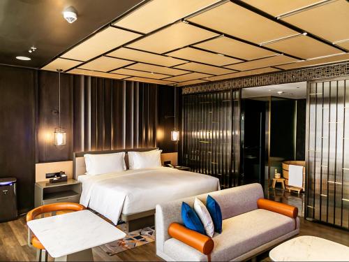 Hotel Okura Manila - Staycation Approved في مانيلا: غرفة نوم بسرير واريكة وكرسي