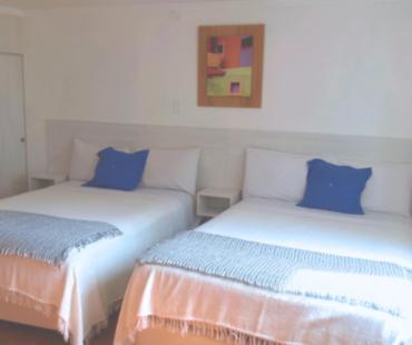 two beds with blue pillows in a room at Hotel Mediterraneo Quito in Quito