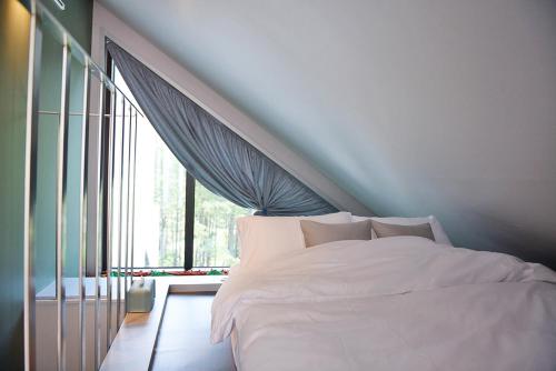 a bedroom with a white bed and a large window at Forestel Meomul in Suncheon