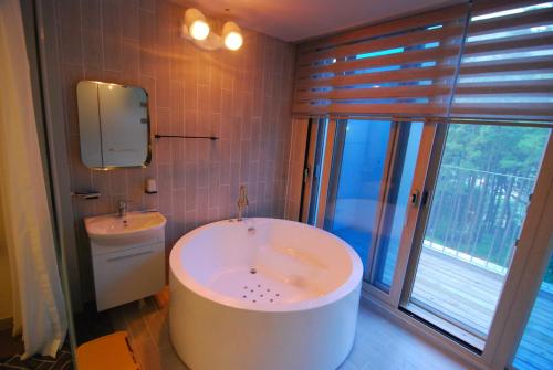 a bathroom with a tub and a sink and a mirror at Forestel Meomul in Suncheon