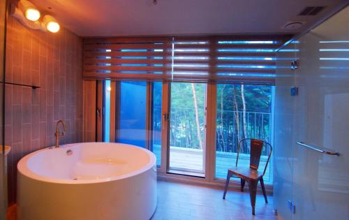 a bathroom with a tub and a chair and a window at Forestel Meomul in Suncheon