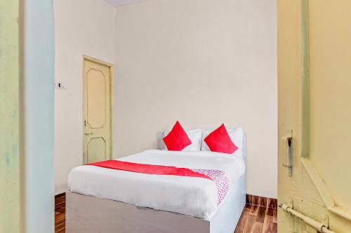 ein Schlafzimmer mit einem großen weißen Bett mit roten Kissen in der Unterkunft OYO Shree Balaji Lodging in Chikalthān