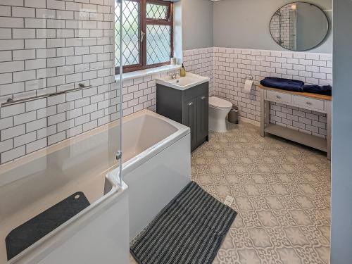 a bathroom with a tub and a toilet and a sink at Pixies Wood Cottage in Ludham