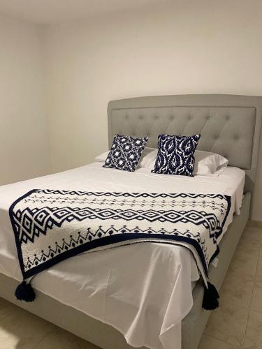 een bed met een zwart-witte deken en kussens bij Casa Verbena in Cisneros