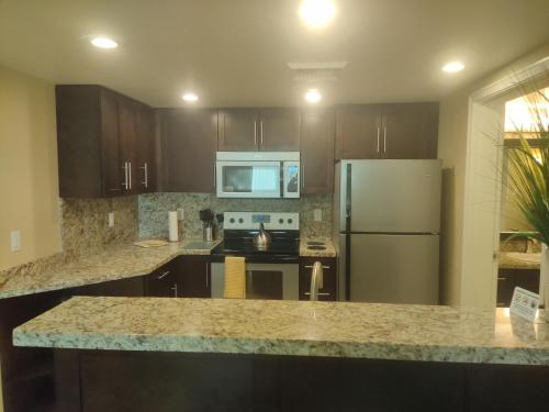 a kitchen with wooden cabinets and a stainless steel refrigerator at 1 bedroom condo F1 / Superbowl Availability in Las Vegas