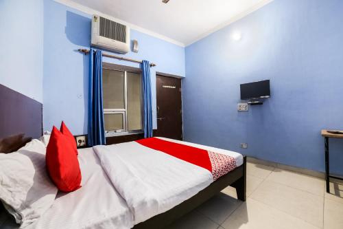 um quarto com uma cama com almofadas vermelhas e uma televisão em OYO 67226 Om Hotel em Neemrana