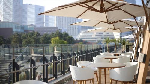 a row of tables and chairs with umbrellas on a balcony at InterContinental Yokohama Pier 8 by IHG in Yokohama