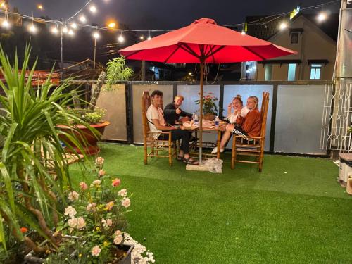 a group of people sitting at a table under an umbrella at Redhouse Dalat Hotel in Da Lat