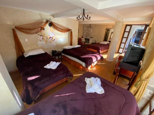 a hotel room with two beds and a television at Golden Rest Ecuador in Latacunga