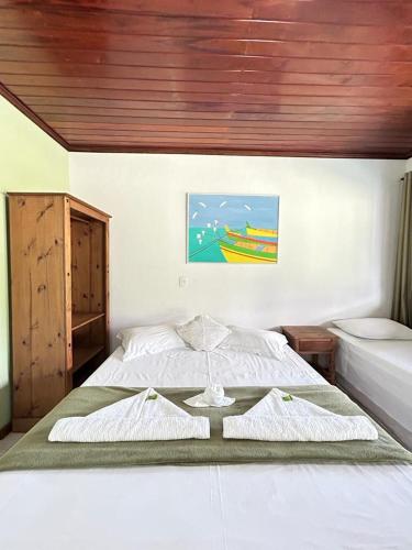 a bedroom with two beds and a painting on the wall at Pousada Paraty Graziela in Paraty
