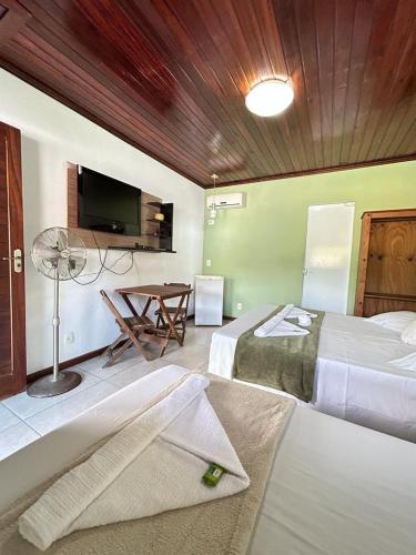 a bedroom with two beds and a table with a tv at Pousada Paraty Graziela in Paraty