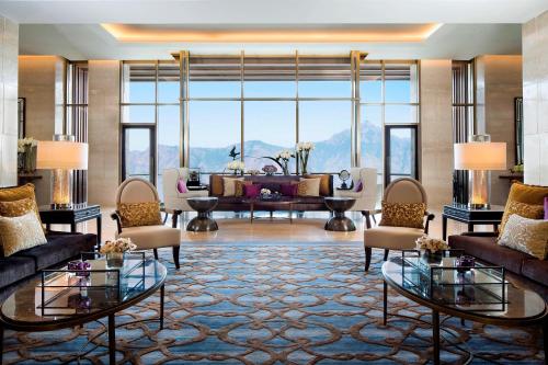 a living room with couches and a large window at JW Marriott Mussoorie Walnut Grove Resort & Spa in Mussoorie