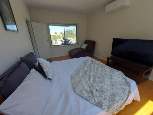 a bedroom with a bed and a chair and a window at Town, Train, Pubs & River all close by in Echuca