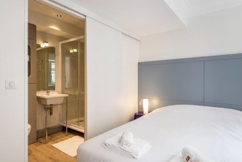 une chambre avec un lit blanc et une salle de bain dans l'établissement Les Capucins - Lyon 1er, à Lyon