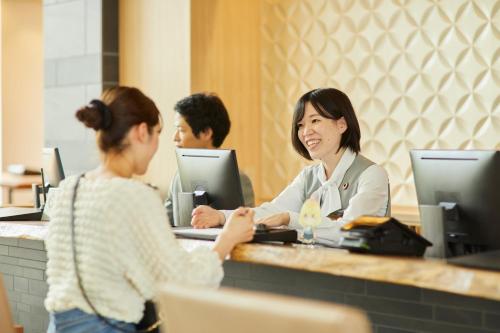 een vrouw die aan een balie in een restaurant zit bij Kanazawa Sainoniwa Hotel in Kanazawa