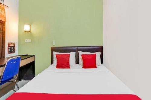 a large bed with red pillows and a blue chair at Pondok Inap Shofwa in Sedati
