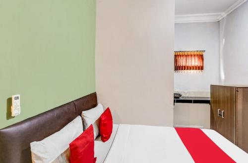 Sedati的住宿－Pondok Inap Shofwa，一间卧室配有红色和白色枕头的床