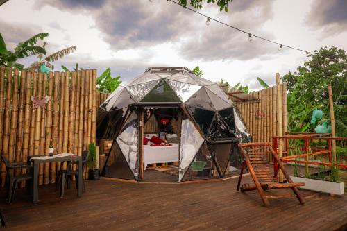 ein Zelt auf einer Terrasse mit einem Tisch und Stühlen in der Unterkunft Happy Glamping Quindio - Tipo Domo Traslúcido in Calarcá