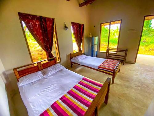 2 Betten in einem Zimmer mit 2 Fenstern in der Unterkunft Nelumgala Cottage -Village Experience in Galewela