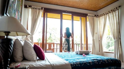a woman looking out the window of a bedroom at Jati 3 Bungalows in Ubud