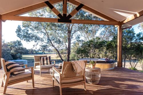 a patio with chairs and a table with a view at Highgrove Cottage in Eurunderee