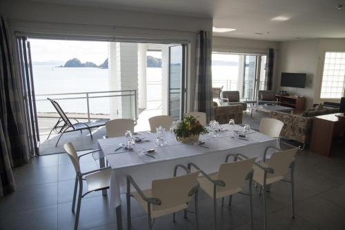 a dining table and chairs in a living room with the ocean at The Waterfront Suites - Heritage Collection in Paihia