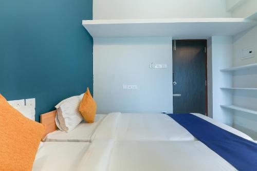 a white bed in a room with a blue wall at Hotel O Maraimalai Nagar in Singapperumālkovil