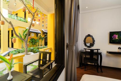 a living room with yellow walls and a room with a window at Lantern Boutique Hoi An in Hoi An