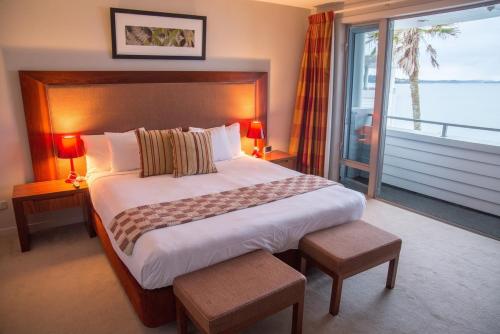 um quarto com uma cama grande e uma janela grande em The Waterfront Suites - Heritage Collection em Paihia