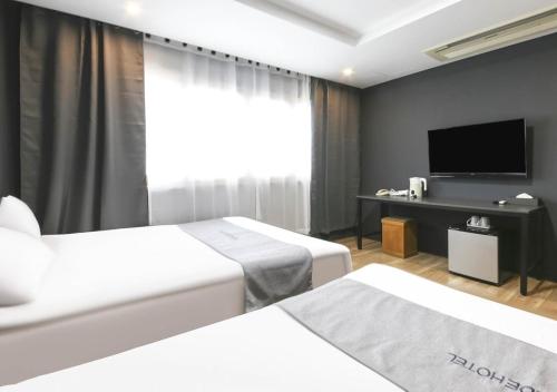 済州市にあるチェジュ パークサイド ツーリスト ホテルのベッド2台、薄型テレビが備わるホテルルームです。