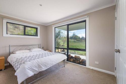 a bedroom with a bed and a large window at The Lake House Meadowbank: Waterfront Retreat in Ellendale