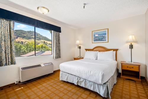 una camera d'albergo con un letto e una grande finestra di DOWNTOWN SLO INN - SAN LUIS OBISPO a San Luis Obispo