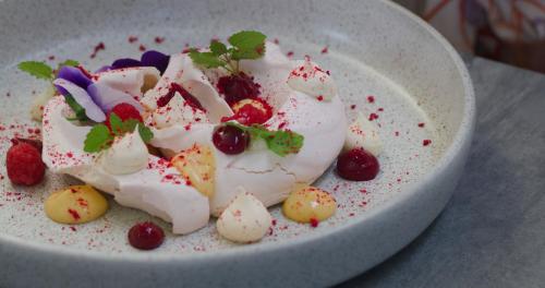 a white bowl of dessert with berries and whipped cream at Essence Peregian Beach in Peregian Beach