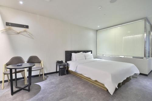 a bedroom with a large white bed and a table at Busan Platinum Hotel Nampo in Busan