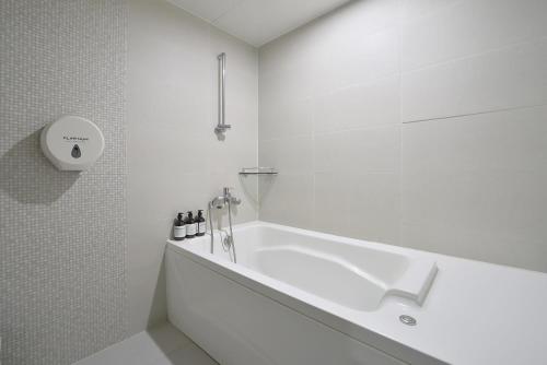 a white bathroom with a tub and a sink at Busan Platinum Hotel Nampo in Busan
