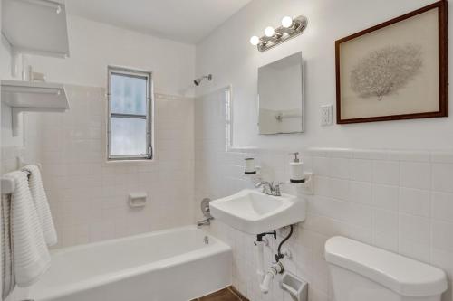 a white bathroom with a sink and a toilet and a tub at 2Bd Holiday Retreat West Palm Beach Art Scene in West Palm Beach
