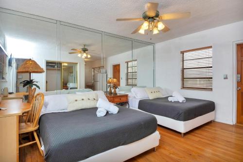 a bedroom with two beds and a desk and a ceiling fan at Hollywood Oasis: Lovely Studio with Free Parking in Hollywood