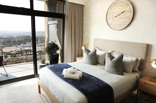 a bedroom with a large bed with a clock on the wall at Menlyn Trilogy - 2 Bedroom & Great Views - No Loadshedding in Pretoria