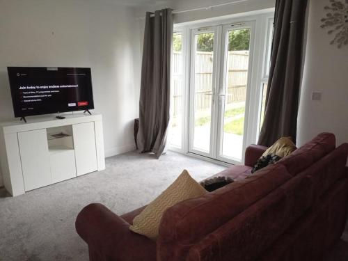 a living room with a couch and a flat screen tv at Stansted Airport Serviced Accommodation x DM for Weekly x Monthly Deals by D6ten Homes Ltd in Takeley