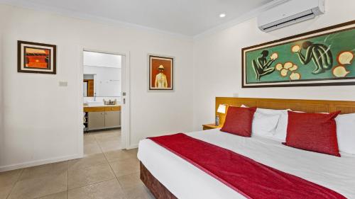 a bedroom with a large bed with red pillows at The Pearle of Cable Beach in Broome